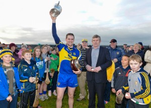 Colin Ryan of Newmarket lifts the Clare Champion Cup following the win over Inagh-Kilnamona in the Clare Champion Cup final at Clarecastle. To the right is Joe Cooney, vice Chairman of Clare GAA who made the presentation.