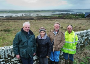 Representatives of three of the four families trapped by flooding, seen in the background, at Kilcredaun, Carrigaholt; From left; Jim and Bernie O Brien, Pat Gavin and Stephen Rowan. Photograph by John Kelly.