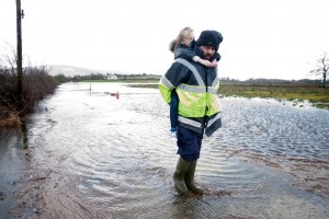 Rory Moloney with his eight-year-old daughter, Caoimhe at the completely submerged roadway to their home near O'Callaghan's Mills. Photograph by Arthur Ellis