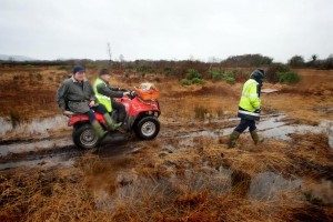 Ger Mulqueen (front) and James Pepper on the Quad with Rory Moloney walking alongside use the only means available to access their homes through dangerous bogland , the roadway to their homes near O'Callagha'ns Mills in Clare is completely submerged. Photograph by Arthur Ellis