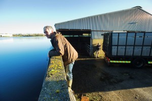 John Nolan watches the flooding as it rises over his farm at Corker, Kiltartan. In the background, haulier Michael Lynskey locks up John’s cattle in a truck for evacuation from the slatted house before the water comes in.