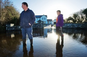 Tom Nolan and his son, Brian, outside their house at Kiltartan, where the floodwater continues to rise and the public road is blocked.  