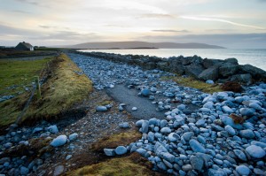 A road covered by rocks and cut off following the latest high seas and gales at The Flaggy Shore in New Quay. Photograph by John Kelly.