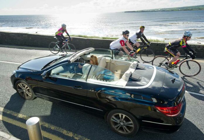 Everyone to their own as the cyclists pass an open top car on the way into Lahinch during the second day of the Clare 250 Cycle. Photograph by John Kelly.