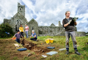 Archaeologist Graham Hull recording information uncovered on an archaeological dig in the shadow of Quin Abbey. In the background are volunteers Ritchie Jones, Ita Lawton, Fiona Clancy and Mary Howard. Photograph by John Kelly.