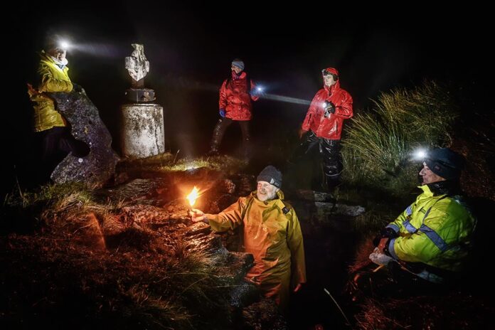 New Year's Eve at St Enda's Well, Slieve Elva, Fanore. Tom Doherty of Doolin Coastguard lights a torch to leave inside the well chamber, in memory of all who have lost their lives at sea over the past year, Looking on are, Celina Kennedy, David Courtney, former Coastguard helicopter pilot, John Galvin, MD Clare Champion and Joe Queally of the RNLI. Photograph by John Kelly.